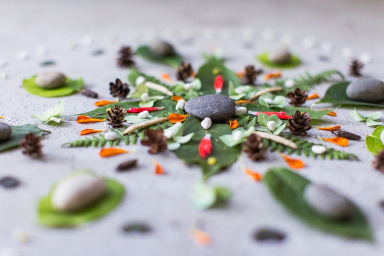 A creative arrangement of stones, leaves, and petals in a nature-inspired pattern.