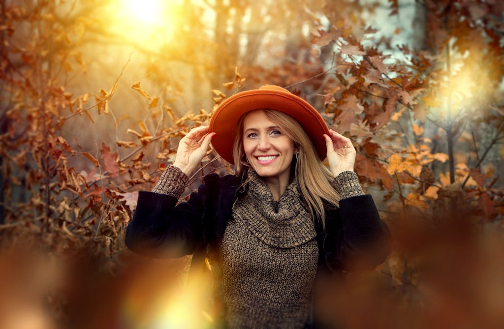Woman enjoying a sunny autumn day in the forest, surrounded by vibrant fall leaves.